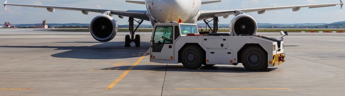 Airplane on airport concrete runway with ground support vehicle