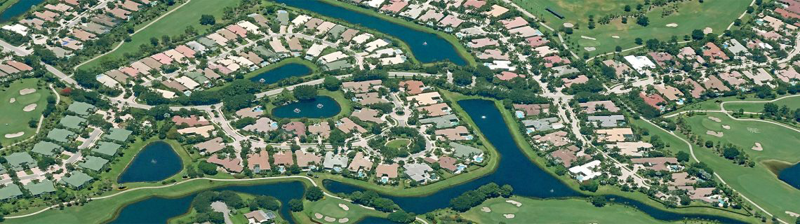 Aerial view of a private community with asphalt roads and concrete driveways and sidewalks